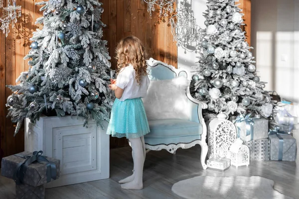 Kız arkasında duruyor ve Noel ağacını süslüyor.