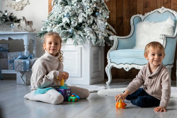 Hermano y hermana juegan en el suelo en un ambiente de Año Nuevo — Foto de Stock