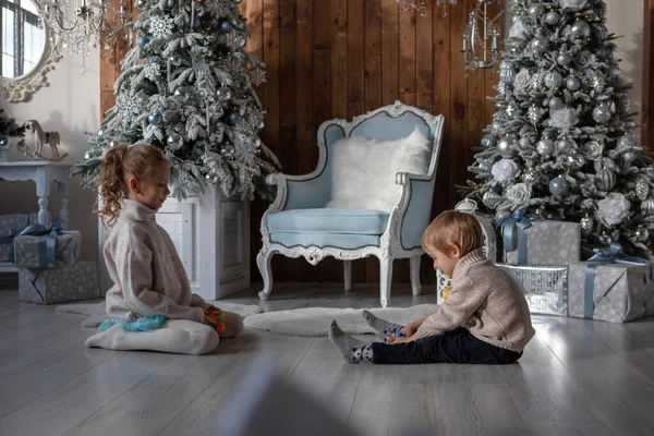 Erkek ve kız kardeş yeni yıl atmosferinde yerde oynuyorlar.