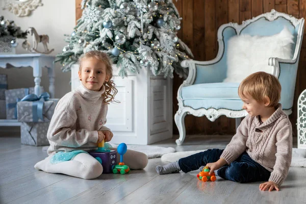 Hermano y hermana juegan en el suelo en un ambiente de Año Nuevo — Foto de Stock