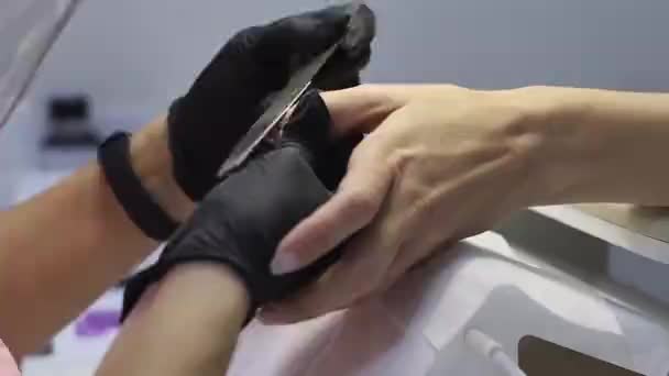 Le maître manucure en gants jetables noirs corrige les ongles — Video