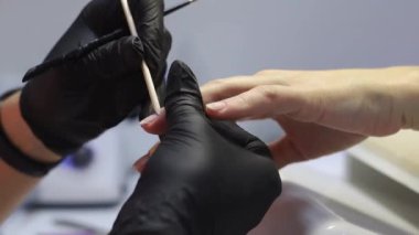 Manikürcünün çalışmasında turuncu bir çubuk. Tırnağın hazırlanması. 