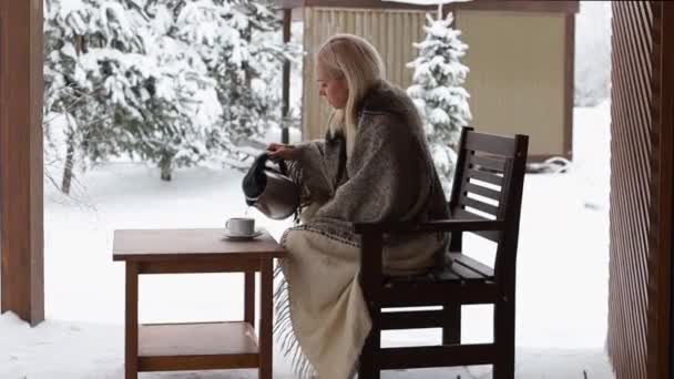 Flickan är insvept i en filt och häller kokande vatten i en mugg — Stockvideo