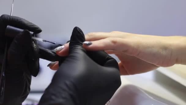 Мастер применяет и распределяет специальный инструмент на ногти. — стоковое видео