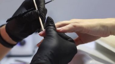 Manikürcünün çalışmasında turuncu bir çubuk. Tırnağın hazırlanması. 