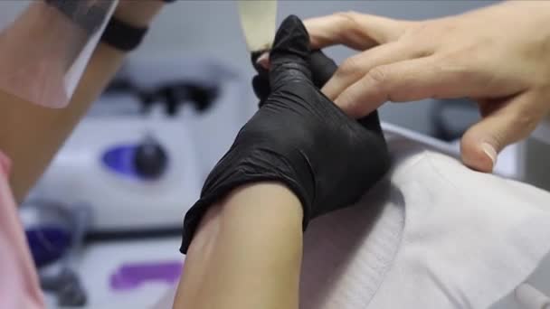 Der Manikürmeister in schwarzen Einmalhandschuhen korrigiert die Nägel — Stockvideo