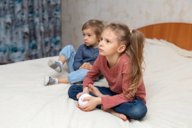 Bir kız ve bir oğlan küp şeklinde bir projektörle bir yatakta oturuyorlar.