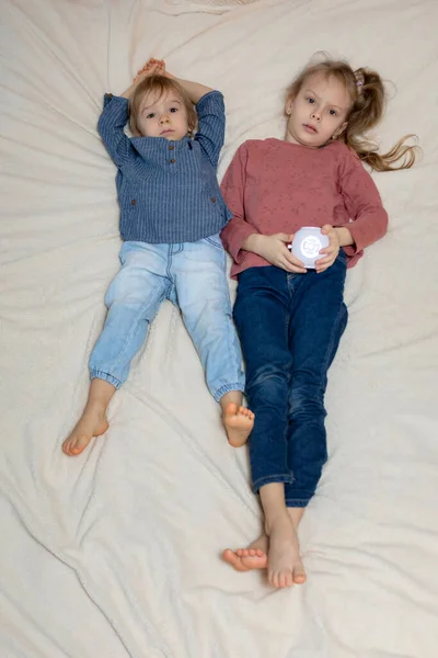 A boy and a girl are lying on the bed with a projector — Fotografia de Stock