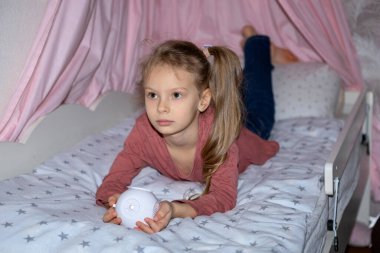 Kızın elinde film izlemek için küçük bir projektör var.