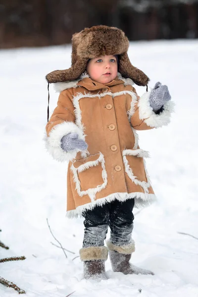 Un bambino in pelliccia invernale, cappello e stivali di feltro in una foresta innevata — Foto Stock