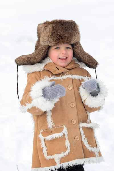 Un bambino in pelliccia invernale, cappello e stivali di feltro in una foresta innevata — Foto Stock