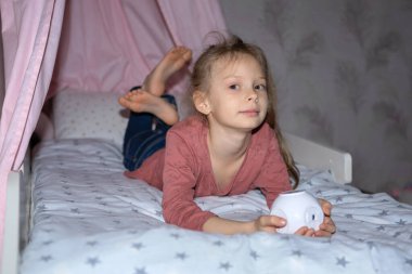 Kızın elinde film izlemek için küçük bir projektör var.