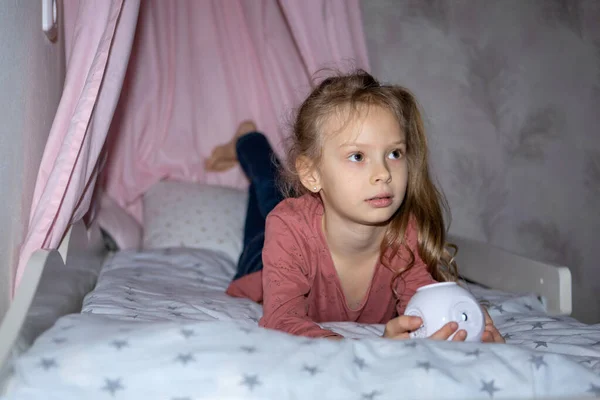 The girl has a small portable projector in her hands for watching movies — Fotografia de Stock