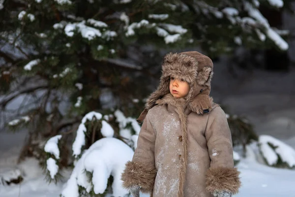 Un ragazzo in inverno vestiti popolari russi, il suo cappello è scivolato lateralmente sopra i suoi occhi — Foto Stock