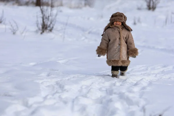 Ребенок в зимней шубе, шляпе и войлочных сапогах в заснеженном лесу — стоковое фото