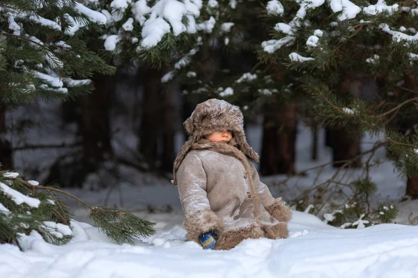 Un ragazzo carino in pelliccia e un cappello con paraorecchie cammina in inverno — Foto Stock