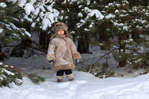 Un ragazzo carino in pelliccia e un cappello con paraorecchie cammina in inverno — Foto Stock