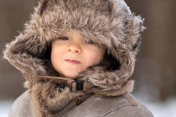 Un ragazzo carino con un cappello con i paraorecchie guarda da qualche parte in lontananza — Foto Stock