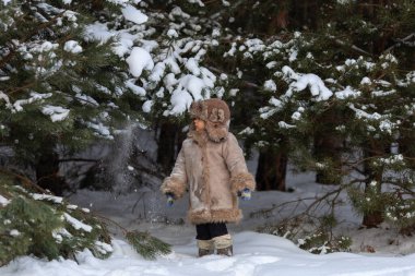 Kürklü ve kulaklıklı şirin bir çocuk kışın yürür.
