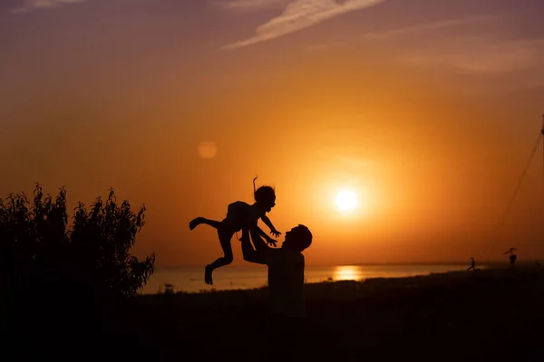 Gün batımına karşı bir adam ve bir çocuğun silueti. Baba oğlunu büyütüyor. 
