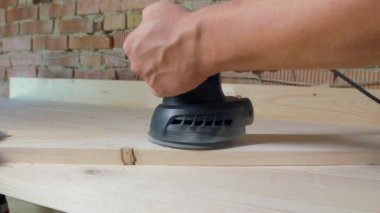 Marangoz tahtayı zımpara makinesiyle parlatır..