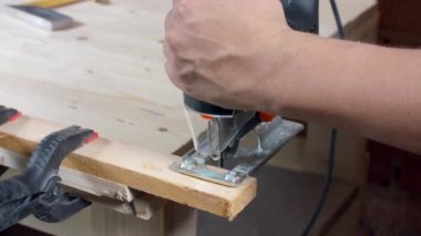 Marangoz elektrikli bir yapbozla tahta testereyle kesiyor.
