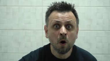 Büyüteçle şaşırmış bir adamın portresi. Garip, dağınık bir adam büyüteçten bakıyor..