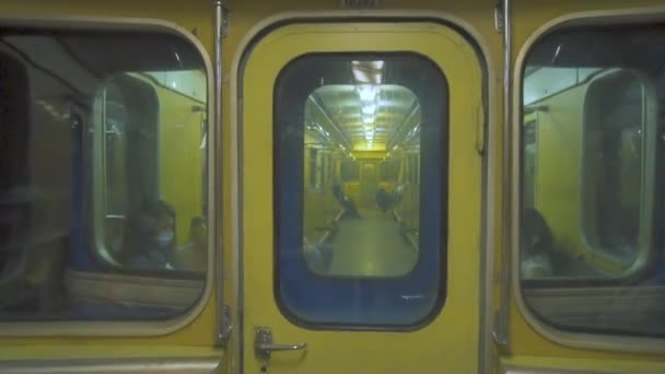 人们乘坐一辆半空的复古地铁车 地铁车通过玻璃 在乌克兰的地下戴面具的人坐地铁 — 图库视频影像