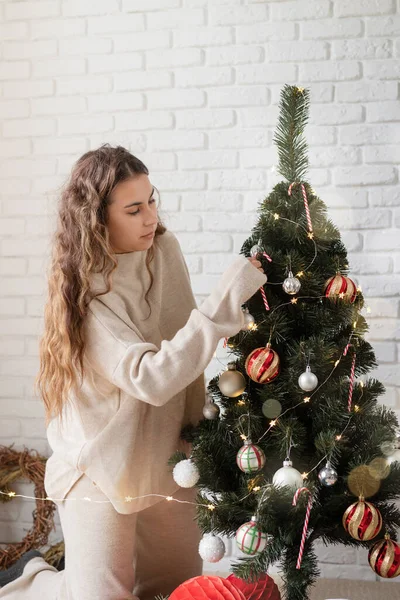 Mujer atractiva joven decorando el árbol de Navidad con luces de hadas — Foto de Stock