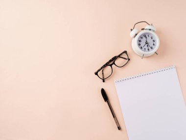 Üst düzey masa düzenlemesi. Zaman yönetimi, planlama konsepti. Bej arkaplan üzerinde boş takvim, gözlük, alarm saati ve kalem, metin için kopyalama alanı