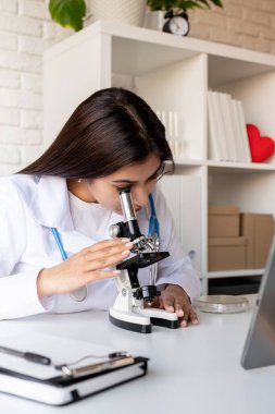 Sağlık hizmeti, sigorta konsepti. Mikroskop kullanan genç doktor ya da bilim kadını örneklerle çalışıyor.