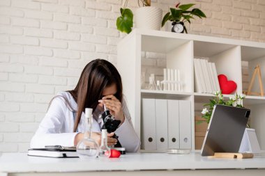 Sağlık hizmeti, sigorta konsepti. Mikroskop kullanan genç doktor ya da bilim kadını örneklerle çalışıyor.