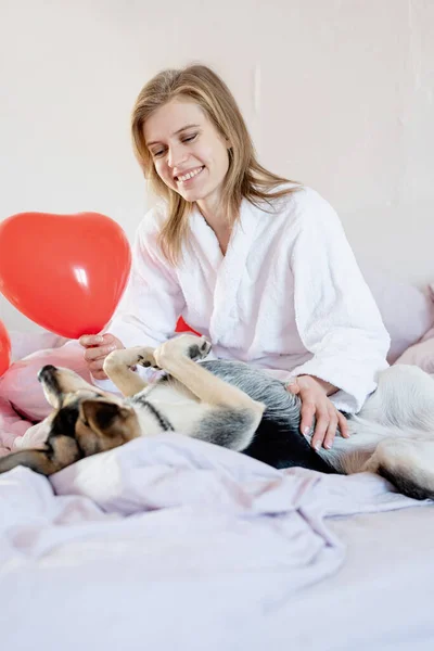 Giovane donna seduta nel letto con il suo cane — Foto Stock