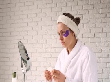 Güzel bir kadın cildine bakıyor, göz bandı takıyor.