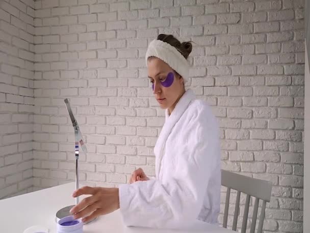 Красивая женщина заботится о своей коже, нанося повязки на глаза — стоковое видео