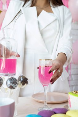 Doğum günü partisi. Doğum günü masaları. Beyaz parti kıyafetleri içinde çekici bir kadın doğum günü masasını kek, pasta, badem kurabiyesi ve diğer şekerlerle hazırlıyor.