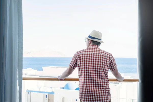 휴가요 모자를 잘생긴 발코니에 바다를 바라보고 있습니다 — 스톡 사진