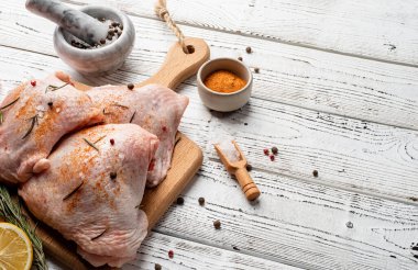 Kesme tahtasının üzerinde derisi olan dilimlenmiş tavuk butları. Beyaz ahşap arka plan. Boşluğu kopyala