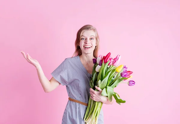 International Women\'s Day. pretty charming brunette young woman dressed yellow clothes holding tulip bunch isolated pink color background