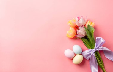Tatil için ev dekorasyonu. Paskalya arkaplanı, pembe arka planda yumurtalar ve laleler, üst manzara düz.