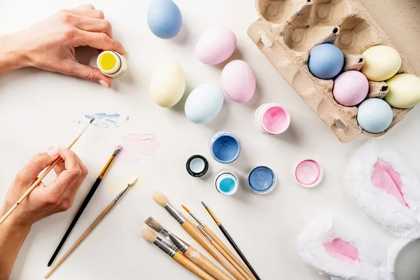 Paskalya için hazırlanan kadın. Tatil için ev dekorasyonu. Paskalya yumurtalarını pastel boyalarla boyamak, üst görünüm düzlük, tatil arka planı