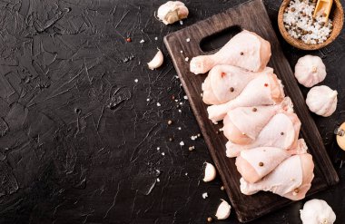 Kesme tahtasında derisi olan dilimlenmiş tavuk bacağı. Karanlık arka plan. Üst görünüm