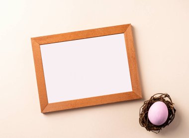 Renkli paskalya yumurtası olan ahşap çerçeve bej arka planda yatıyordu