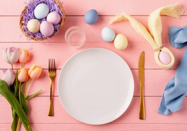Mutlu Paskalyalar. Paskalya ziyafeti için masa hazır. Paskalya yumurtaları, tavşanlar, laleler ve çatal bıçak takımları.