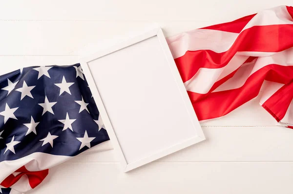 Amerikan ulusal bayrağının ahşap arka planında model tasarımı için boş beyaz fotoğraf çerçevesi