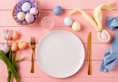 Mutlu Paskalyalar. Paskalya ziyafeti için masa hazır. Paskalya yumurtaları, tavşanlar, laleler ve çatal bıçak takımları.