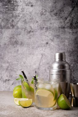 fresh summer caipirinha cocktail on concrete background with green fruit lime on table
