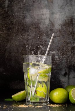 fresh summer caipirinha cocktail on concrete background with green fruit lime on table