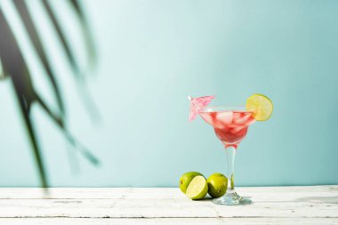Fresh strawberry alcohol cocktail. Fresh summer cocktail with strawberry, lime and ice cubes on blue background with copy space