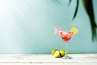 Fresh strawberry alcohol cocktail. Fresh summer cocktail with strawberry, lime and ice cubes on blue background with copy space